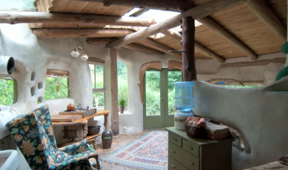 Cob house interior with wooden beams and stone floor