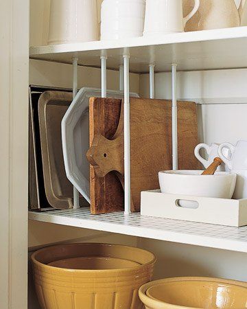 Vertical dividers, like these dividers made from tension rods, are a kitchen organizing essential for keeping trays, baking sheets, and cutting boards in order.