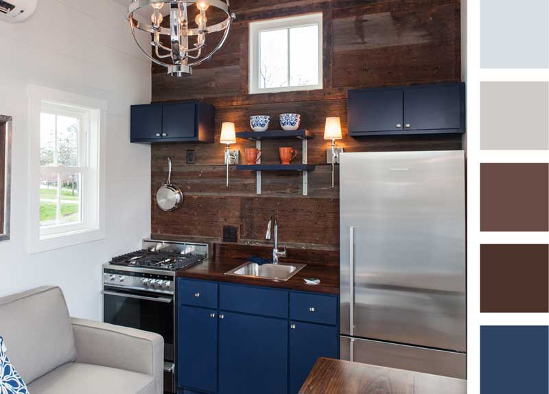 Modern navy and a high-shine countertop make this tiny house kitchen modern and sleek. Open shelving and cupboards, along with a full-size stainless steel fridge, offer storage space.