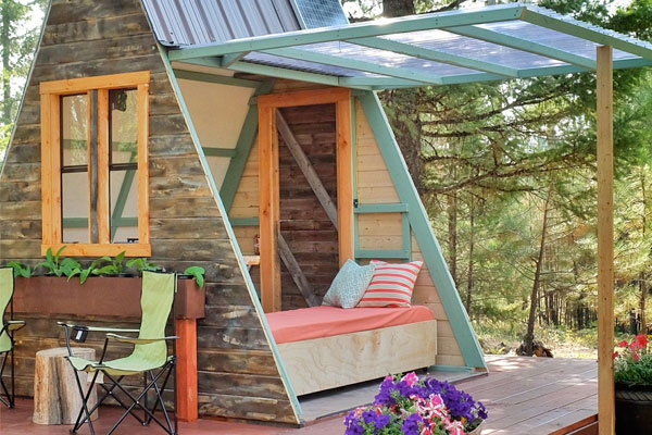 The windowed sides on this A-frame tiny house lift to allow fresh air and create more space.