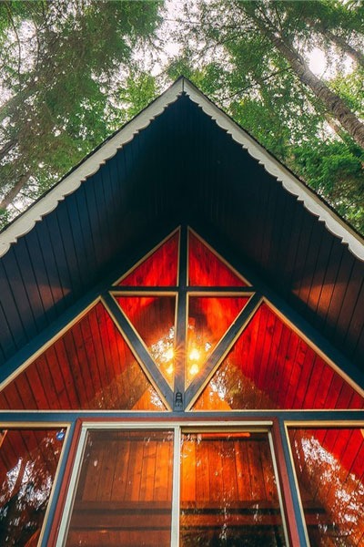 The windowed peak of this A-frame tiny house shows a beautiful high ceiling with plenty of light from the hanging fixture.