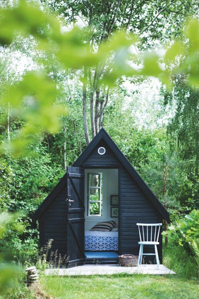 A black A-frame tiny cottage makes a perfect reading nook, outdoor guestroom, or small bedroom.