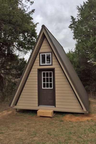 A simple sided A-frame tiny house in tan and brown makes a great starter home for tiny house newbies.