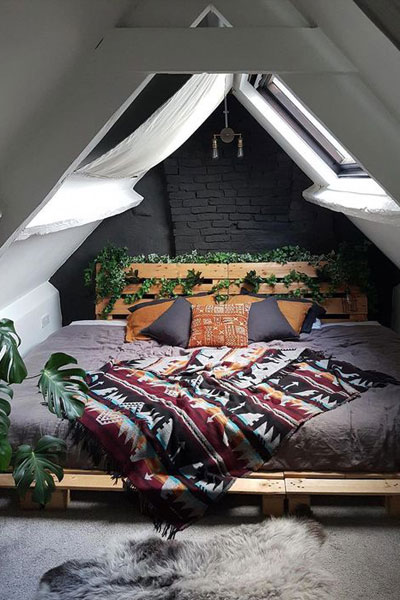 Dark walls look stunning with the sky windows in this A-frame loft bedroom with a large king-sized bed.