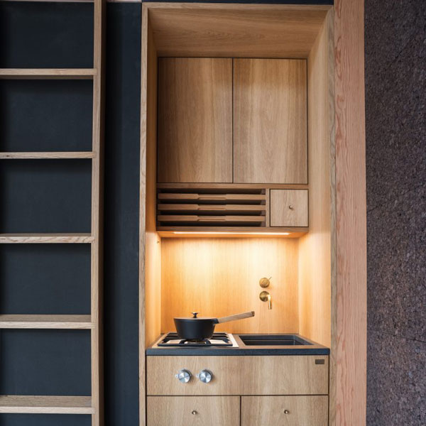 The kitchenette in this A-frame tiny house is small but adequate, with a cupboard, stovetop, and tiny sink.